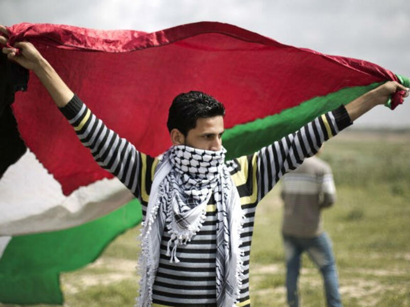A protester waves a Palestinian flag towards the Israeli border fence during a protest marking Land Day at the border between Israel and Gaza Strip on March 30, 2014. (AFP/File)