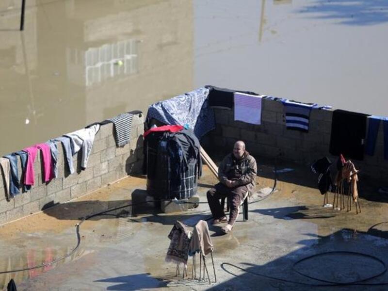 A Palestinian man sits on the roof of his house in a flooded area of Gaza city on December 15, 2013 following heavy rain. A fierce winter storm shut down much of the Middle East the past days. [AFP] 