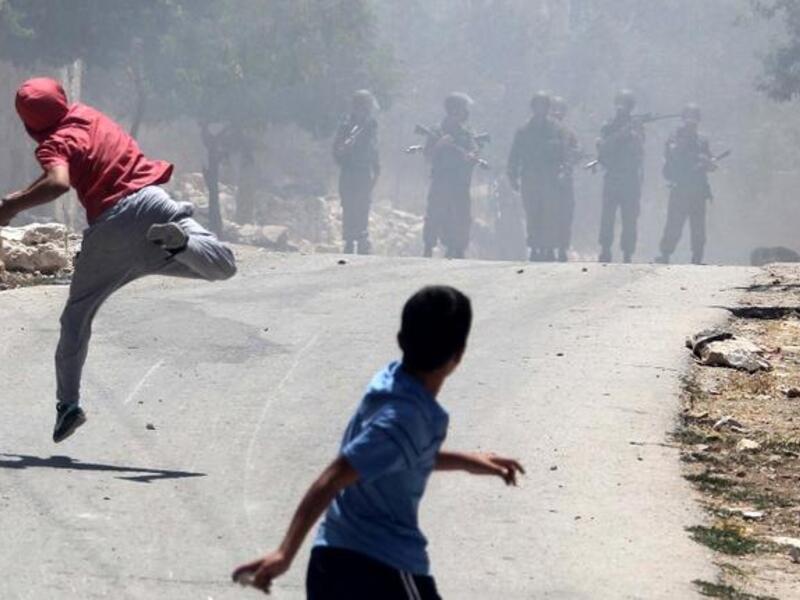 Palestinian protesters throw stones towards Israeli security forces during clashes following a protest against the expropriation of Palestinian land by Israel in the village of Kfar Qaddum near the occupied West Bank city of Nablus (Jaafar Ashtiyeh / AFP)
