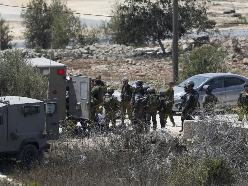 Israeli soldiers surround the body of a suspected Palestinian man who was reportedly shot dead by Israeli troops at the entrance to the West Bank village of Silwad on August 26, 2016. (AFP/Abbas Momani)