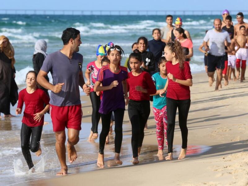 Young Palestinian members of a swimming club, run on the beach during a training session in Beit Lahia in the northern Gaza Strip. (SAID KHATIB / AFP)