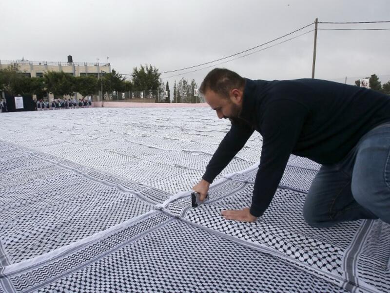 Palestinian students of the Southern Education Direction prepare to apply for the Guinness book of World Records' largest Keffiyeh. (HAZEM BADER / AFP)