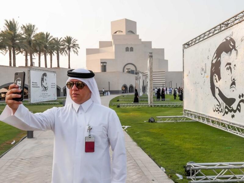 A visitor takes a selfie during an exhibition of artworks depicting Qatari Emir Tamim bin Hamad al-Thani titled "Glorious Tamim: in celebration of national unity " at the garden of the Islamic Museum in Doha on August 20, 2017 (AFP)