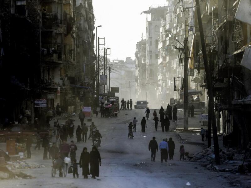 Syrians walk the streets of the formerly rebel-held neighborhood of al-Shaar in Aleppo, which was recaptured by government forces in December 2016. 