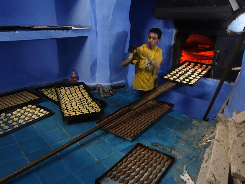 Cookies and sweets are prepared ahead of Eid festivities. While previously families used to do them at home, nowadays many buy them from the market. Here, a man bakes biscuits in the northwestern Moroccan city of Chefchaouen, in the Rif mountains, on June 20, 2017. 