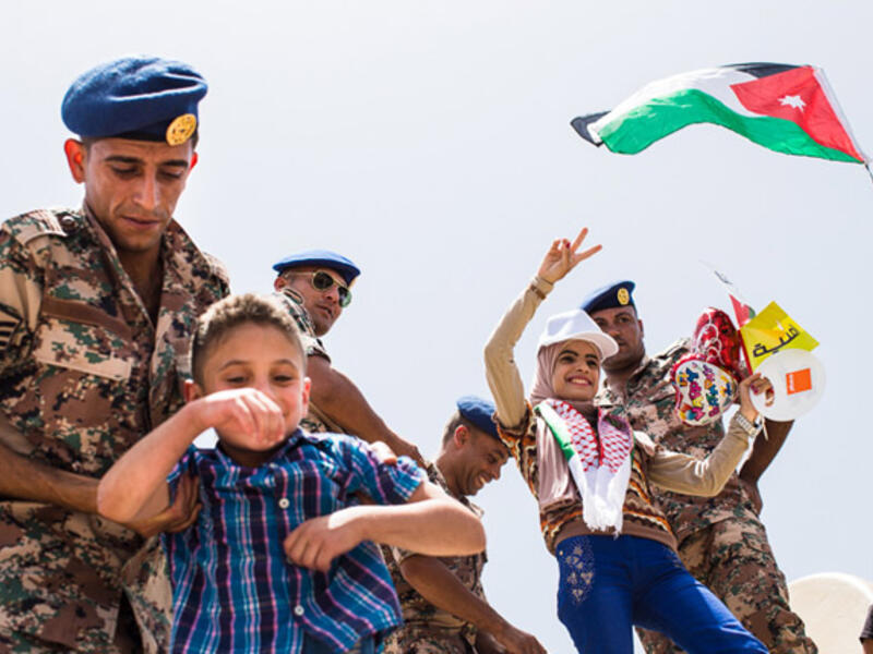 A Jordanian soldier helps a boy get on top of a tank for a photo, while another woman poses with soldiers. Large official and impromptu celebrations were held in Amman to mark the centennial of the Great Arab Revolt on June 3, 2016.