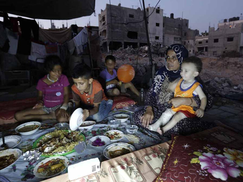 A family in Gaza shares an Iftar dinner during Ramadan. The most popular dish in Palestine is Maqlube, upside-down, which is made with rice, eggplant and meat or chicken, cooked in a pot and flipped up-side down when served. However, due to the situation in Gaza, many families cannot afford buying more than the basic necessities.