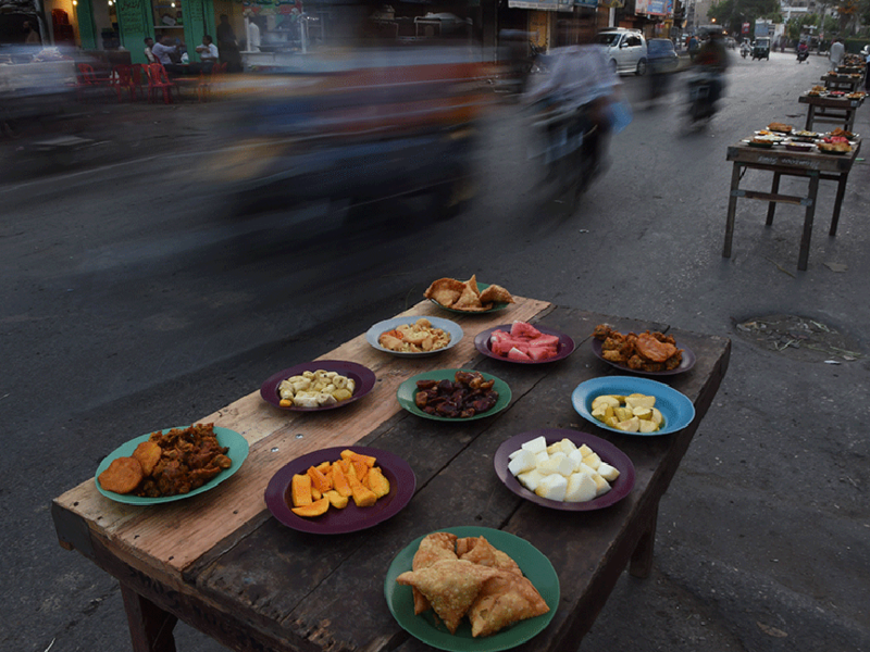 A table in the streets of Karachi, Pakistan, is stuffed with traditional food for Ramadan including samosas (deep fried pastry wraps, filled with minced meat and/or vegetables), pakora (sliced vegetables, dipped in batter and deep-fried) or chatni and namak para (seasoned cracker). Popular sweets during Ramadan include Jabeli.