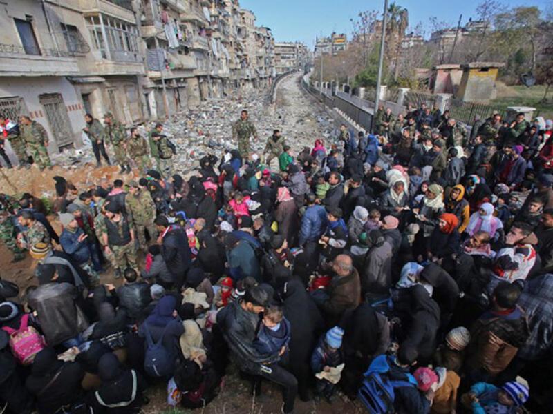Aleppo’s exodus: Syrian residents fleeing violence gather at a checkpoint, manned by pro-government forces, in the Maysaloun neighborhood of Aleppo on December 8, 2016. 