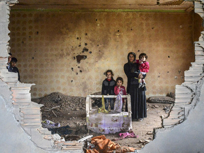 Turkey’s descent into war: A woman and her children stand in the ruins of battle-damaged house in the Kurdish town of Silopi, in southeastern Turkey, near the border with Iraq on January 19, 2016. 