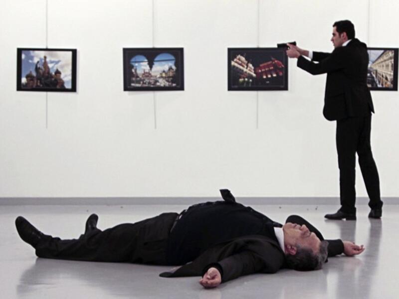 This picture taken on December 19, 2016 shows Andrei Karlov, the Russian ambassador to Ankara, lying on the floor after being shot by Mevlut Altintas (R) during an attack at a public event in Ankara. 