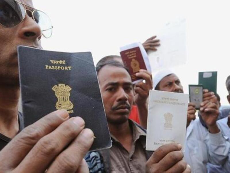 Foreign workers show passports as they wait outside the immigration office in Saudi. [yahoo]