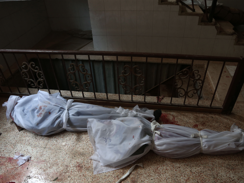 The bodies of civilians who were killed in Syrian army bombardment on the town of Hamouria in the rebel-held enclave of Eastern Ghouta are seen lying on the ground at a make-shift morgue the morning after the attacks on Feb. 20, 2018. 
(ABDULMONAM EASSA / AFP)
