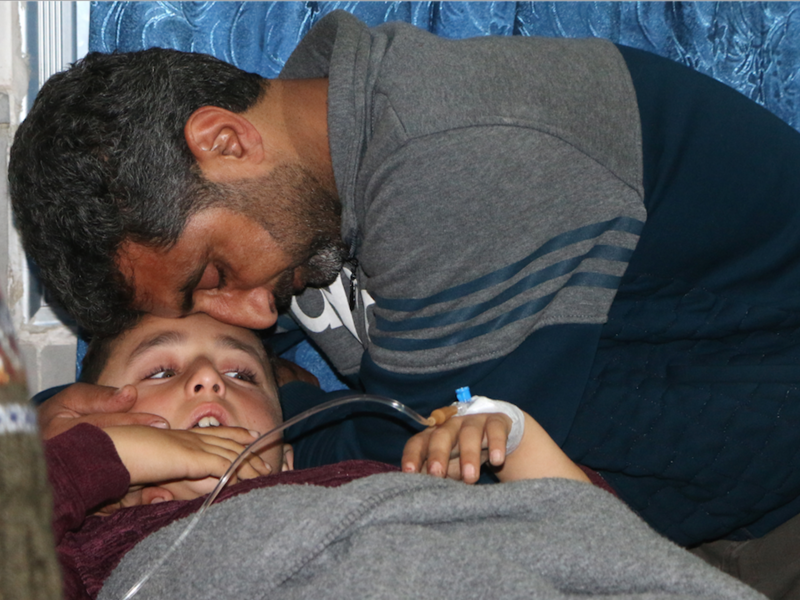 A father comforts his wounded son who was injured in bombardment after he was taken out of intensive care at a hospital in Afrin on Feb. 20, 2018. 
(Ahmad Shafie BILAL / AFP)