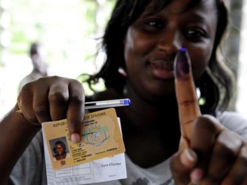 A woman shows documents and a ink-stained finger after voting at a polling station in Abidjan, during the second round of Presidential elections.