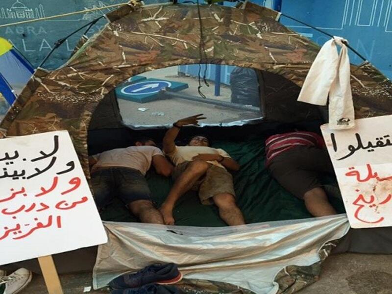 مجموعة من المتظاهرين يعتصمون داخل خيمة مطالبين الحكومة بالإستقالة تحت شعار "استقيلوا ع مزبلة التاريخ".