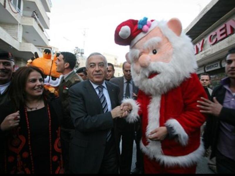 Palestinian prime minister Salam Fayyad (C) shakes hands with a man dressed as Santa Claus as he takes part in the 3rd annual march for unity and peace marking Christmas in the biblical West Bank town of Bethlehem.