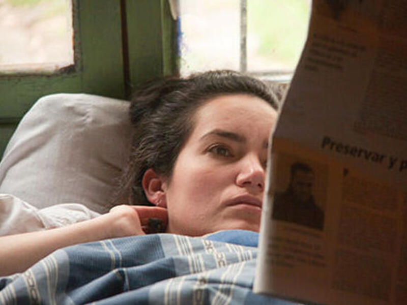 woman reading paper in bed