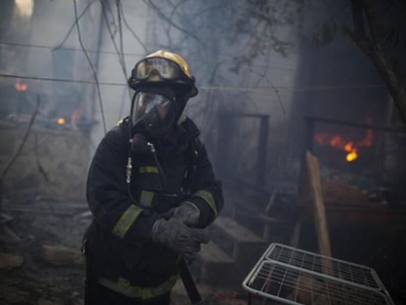 An Israeli firefighter stands at the site of a burning house in the village of Ein Hod, as the massive fire ripping through northern Israel was still incinerating swathes of land, with little sign that Israeli and foreign firefighters were winning the battle to contain it.