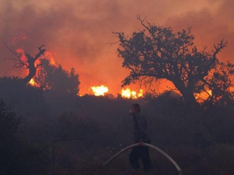 Israeli firefighters work on the slope of a burning hill in Tirat Ha Carmel near the northern city of Haifa