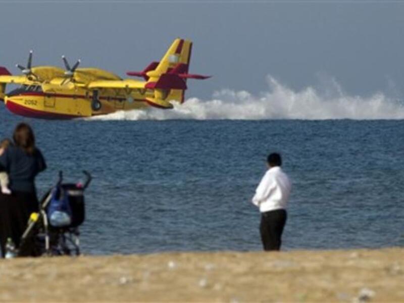 A firefighting airplane prepares to replenish water from the Mediterranean sea near the city of Haifa as the deadly fire which has swept a forest in northern Israel has almost come to an end following a four-day battle aided by aircraft from the around the world.