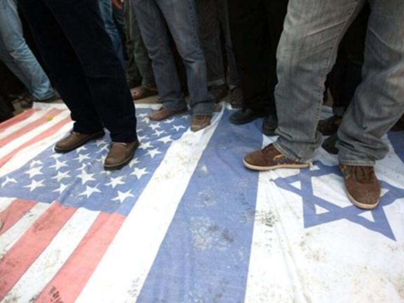 Islamic Jihad supporters walk at the USA and Israeli flag during a demonstration to mark the second anniversary of Israel's three-week offensive on the Gaza Strip.