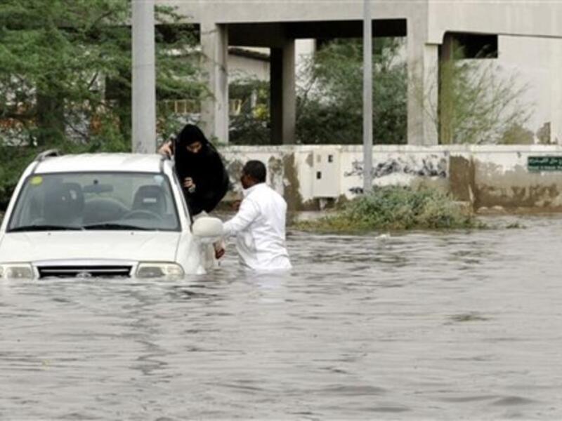 A Saudi man and a woman leave their car after it got stuck in a flooded street following heavy rain in the Red Sea port city of Jeddah.