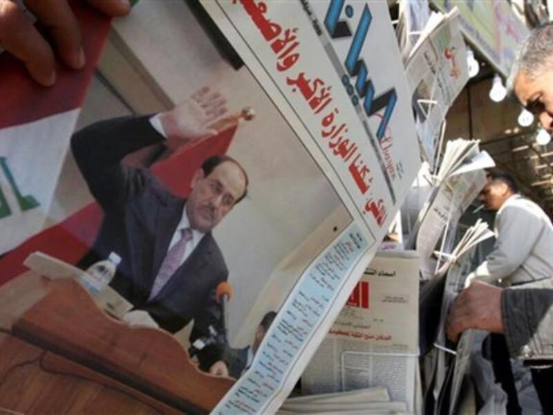 Iraqis pick up newspapers featuring a front-page story on the country's new cabinet at a kiosk in Baghdad, a day after the Iraqi parliament gave Prime Minister Nuri al-Maliki's government a vote of confidence and adopted a 43-point program.