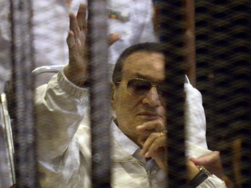Hosni Mubarak waves as he sits behind bars during his re-trial (AFP/ Mohamed Hesham)