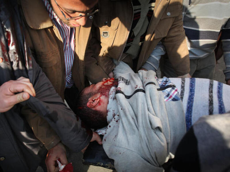 Anti-government protestors carry an injured man.