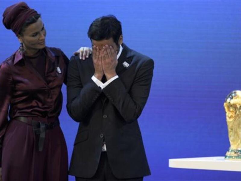 Chairman of Qatar 2022 Bid Committee Sheikh Mohammed bin Hamad Al-Thani (C) is comforted by Sheikha Moza bint Nasser Al-Missned on the podium with the World Cup trophy.
