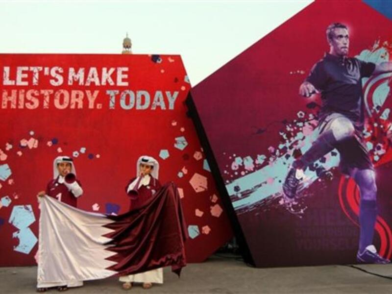 Qatari boys clad in traditional attire wave their national flag at Doha's traditional souk where people are gathering to follow FIFA's decision on who will host the 2022 World Cup.