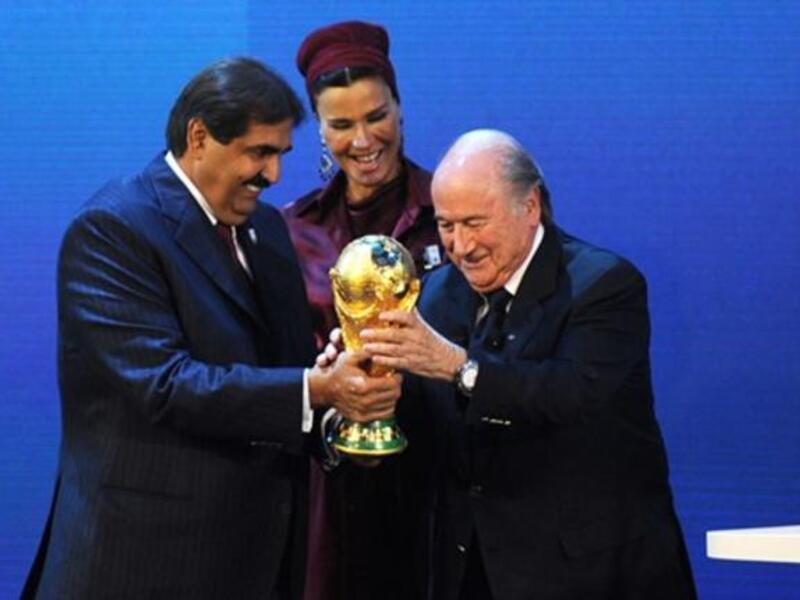 Fifa President Sepp Blatter (R) hands over the World Cup trophy to the Emir of the State of Qatar Sheikh Hamad bin Khalifa Al-Thani (L) and his wife.