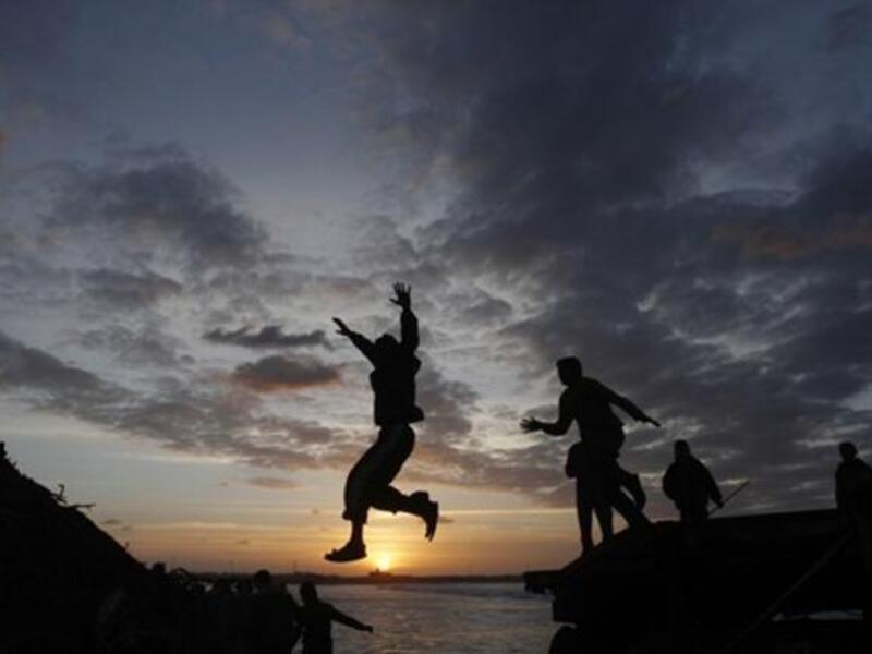 Palestinian boys jump from the top of a sand pile at the beach in Gaza City as they play outdoors during sunset, following storms and heavy rain that poured over the impoverished territory after months of drought.