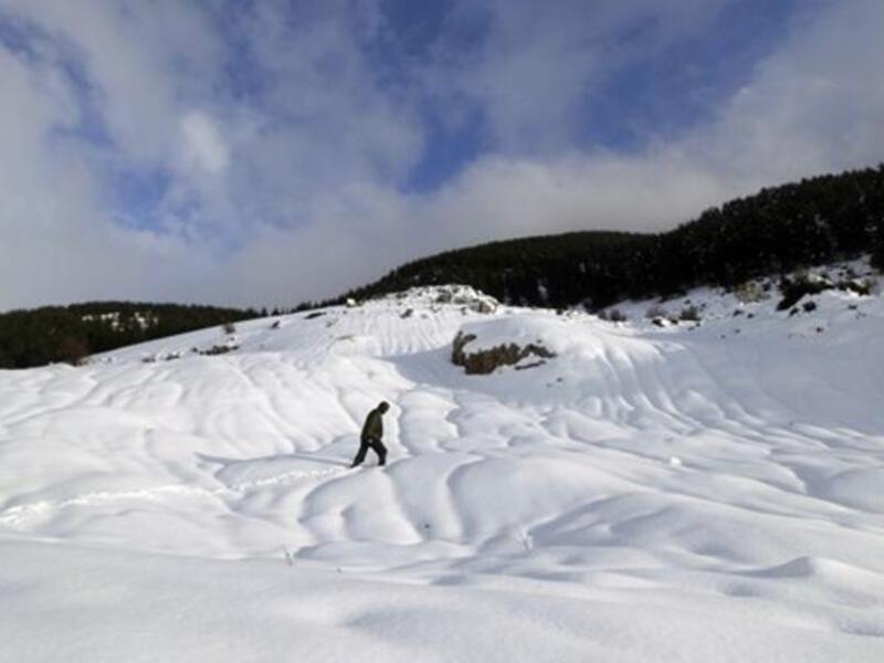 A Lebanese man walks on a snow-covered peak at the cedar trees reserve of Baruk southeast in the Shouf mountains, southeast of Beirut.