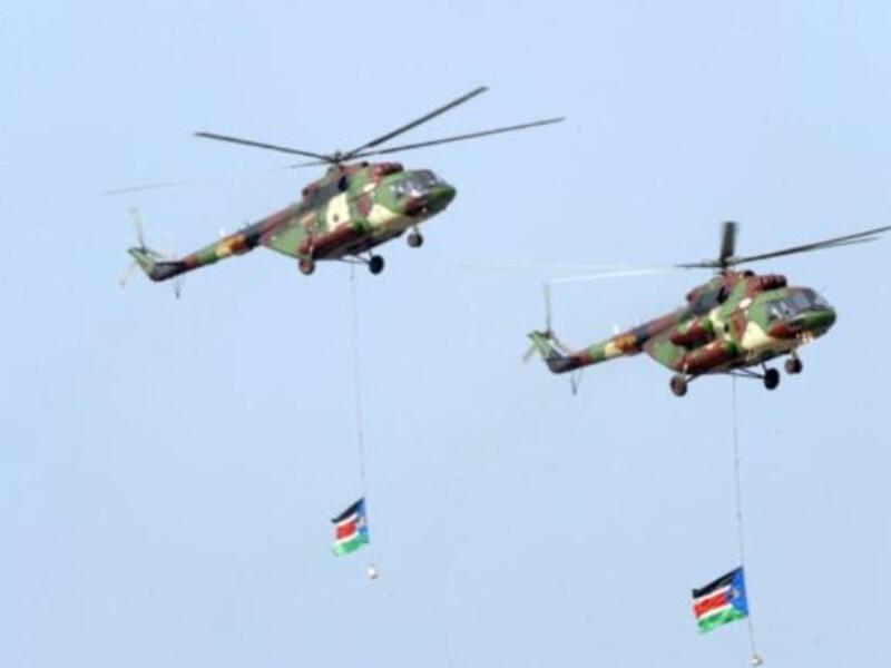 Southern Sudanese military helicopters fly an overpass carrying two Southern Sudan flags during a ceremony in the capital Juba on July 9, 2011 to celebrate South Sudan's independence from Sudan.