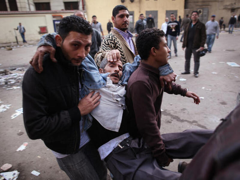 Protesters carry an injured man during clashes with riot police near Tahrir Square.