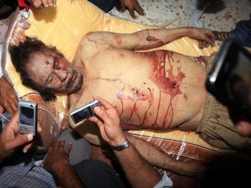الليبيون يلتقطون صورا لجثة معمر القذافي باستخدام هواتفهم النقالة في مصراته بتاريخ ٢٠-١٠-٢٠١١. قتل القذافي بعد أن اقتحم الثوار آخر معاقله في مسقط رأسه سرت وكانت آخر كلمات القذافي: "حرام عليكم.. حرام عليكم.. إنتو ما تعرفوا الحرام؟".