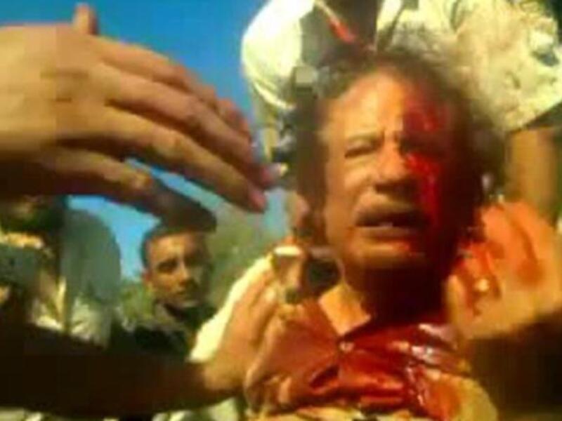 كيف وصل العقيد إلى هذه المصير الدموي؟ ما يزال تسلسل الأحداث غير واضحا بسبب تضارب الأنباء، حيث يقال بأن غارة للناتو استهدفت موكبه في سرت مما دعا مرافقيه للبحث عن مساعدة طبية ساعدت الثوار في العثور عليه ومن ثم إطلاق النار عليه مجددا.