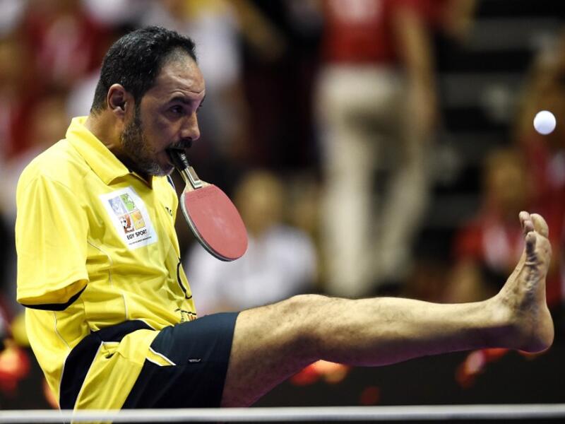 Table Tennis player Ibrahim Hamato of Egypt serves with his foot during an exhibition match at the 2016 World Team Table Tennis Championships at Malawati Stadium in Shah Alam on March 6, 2016.
MANAN VATSYAYANA / AFP