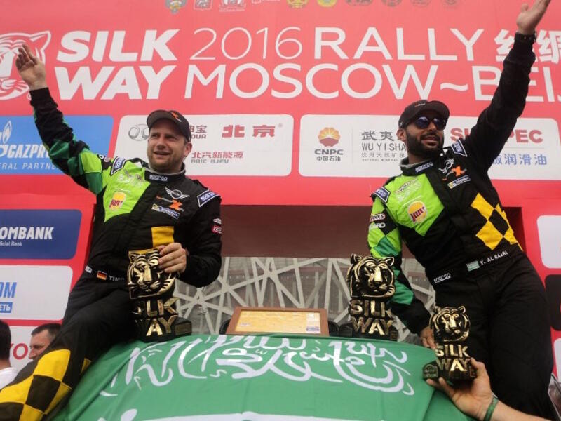 Mini team Yazeed Mohamed al-Rajhi an co-pilot Timoo Gottschalk celebrate with a Saudi flag their second place podium of the Silk Way Rally in Beijing on July 24, 2016.
PATRICK BAZ / AFP
