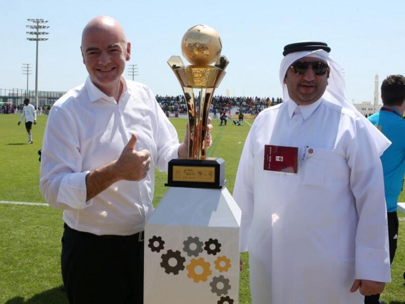 FIFA President Gianni Infantino (L) poses for a picture with the workers football cup trophy during a match ahead of a press conference in the Qatari capital Doha on April 22, 2016. 
KARIM JAAFAR / AFP