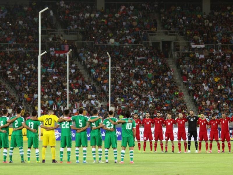 Iraq's (L) and Jordan's starting eleven obeserve a moment of silence ahead of their international friendly football match between Iraq and Jordan at Basra Sports City in Basra on June 1, 2017.
HAIDAR MOHAMMED ALI / AFP