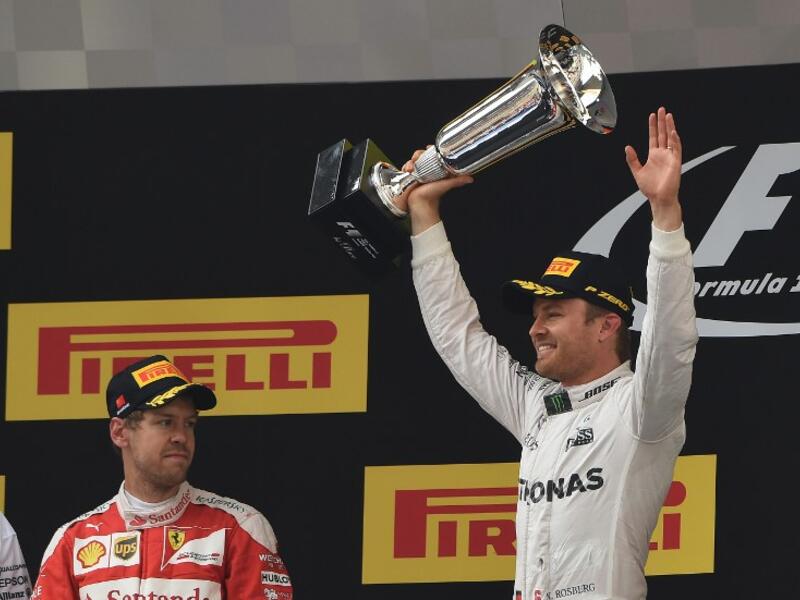 Mercedes AMG Petronas F1 Team's German driver Nico Rosberg (R) celebrates on the podium after winning the Formula One Chinese Grand Prix in Shanghai on April 17, 2016, as second-placed Ferrari driver Sebastian Vettel of Germany (R) looks on.
GREG BAKER / AFP