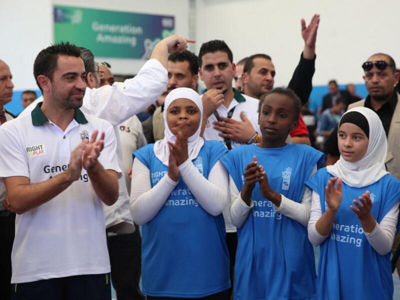 Former Barcelona football player Xavi Hernandez (L), who currently plays for Al-Sadd in the Qatar Stars League, claps as he attends a training session during his visit to the al-Baqaa Palestinian refugee camp near Amman on September 29, 2016.
Khalil MAZRAAWI / AFP