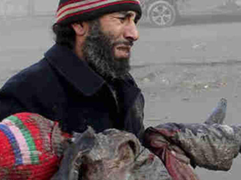A Syrian man cries carrying the body of a child killed by a barrel bomb. [gendynamics]