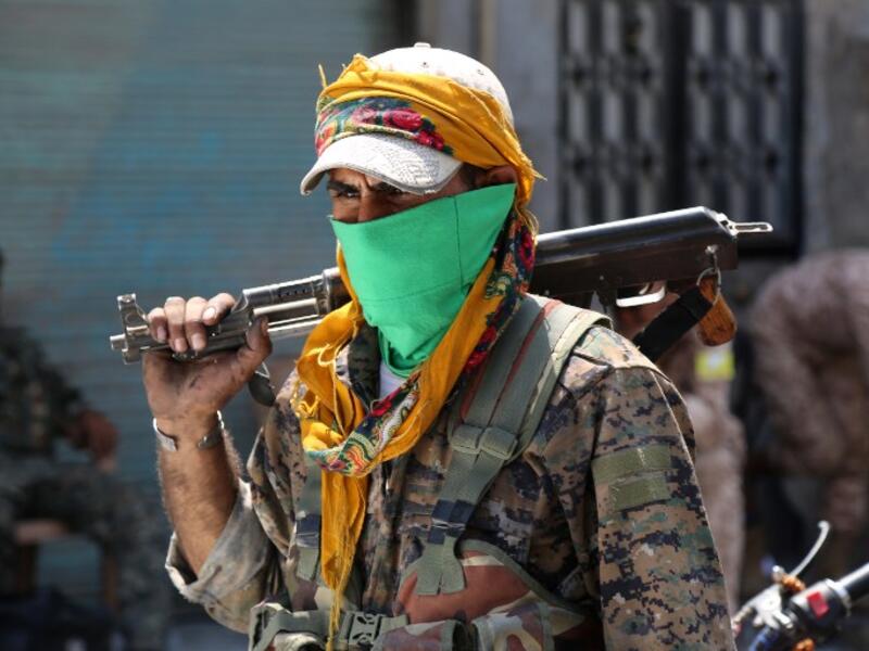 A member of the Syrian Democratic Forces (SDF) walks on a street with his weapon in the northern Syrian town of Manbij on August 7, 2016. (AFP/Delil Souleiman)