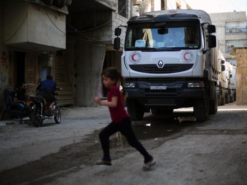 A convoy of Syrian Red Crescent trucks carrying aid drives through Erbin, a besieged rebel-held town east of the Syrian capital Damascus, on June 29, 2016. 