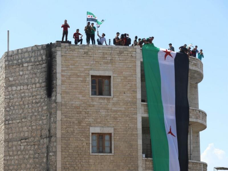Syrian protesters wave the flag of the opposition as they demonstrate against the regime and its ally Russia, in the rebel-held city of Idlib on September 7, 2018. (OMAR HAJ KADOUR / AFP)