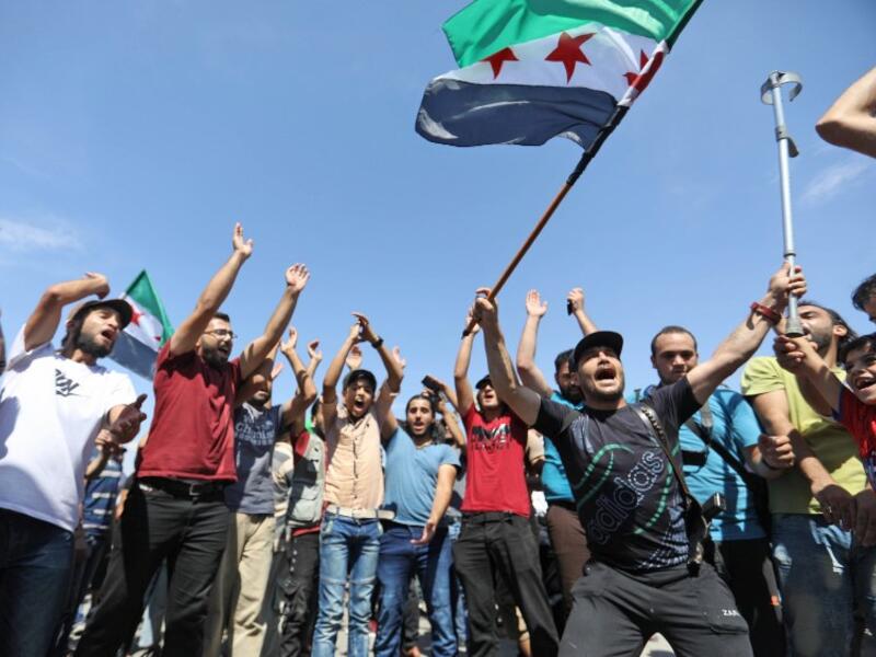 Syrian protesters wave the flag of the opposition as they demonstrate against the regime and its ally Russia, in the rebel-held city of Idlib on September 7, 2018.(OMAR HAJ KADOUR / AFP)